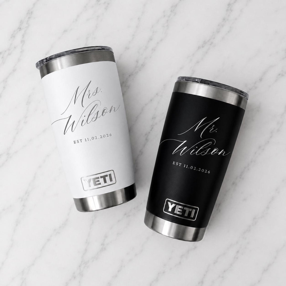 May include: Two stainless steel YETI tumblers, one white and one black, each featuring a silver rim and base. The white tumbler is engraved with 'Mrs. Wilson' and 'EST 11.02.2026', while the black tumbler displays 'Mr. Wilson' and 'EST 11.02.2026'.