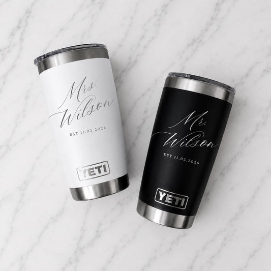 May include: Two stainless steel YETI tumblers, one white and one black, each featuring a silver rim and base. The white tumbler is engraved with 'Mrs. Wilson' and 'EST 11.02.2026', while the black tumbler displays 'Mr. Wilson' and 'EST 11.02.2026'.
